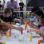 Crianças com óculos de proteção participam de uma experiência científica acompanhadas por adultos