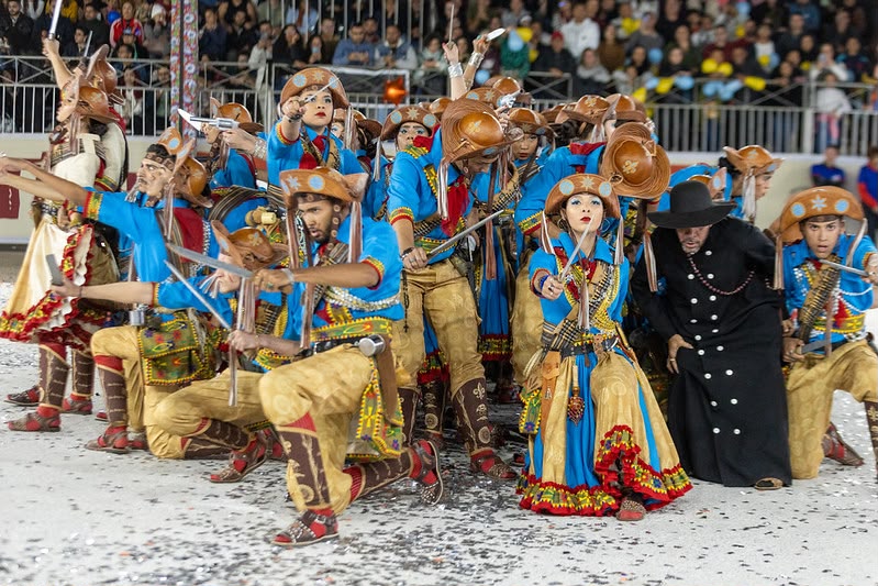 Quadrilha junina se apresenta com figurinos coloridos diante do público