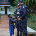 Policiais conversam com um estudante uniformizado próximo a uma escola