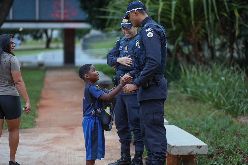 Policiais conversam com um estudante uniformizado próximo a uma escola