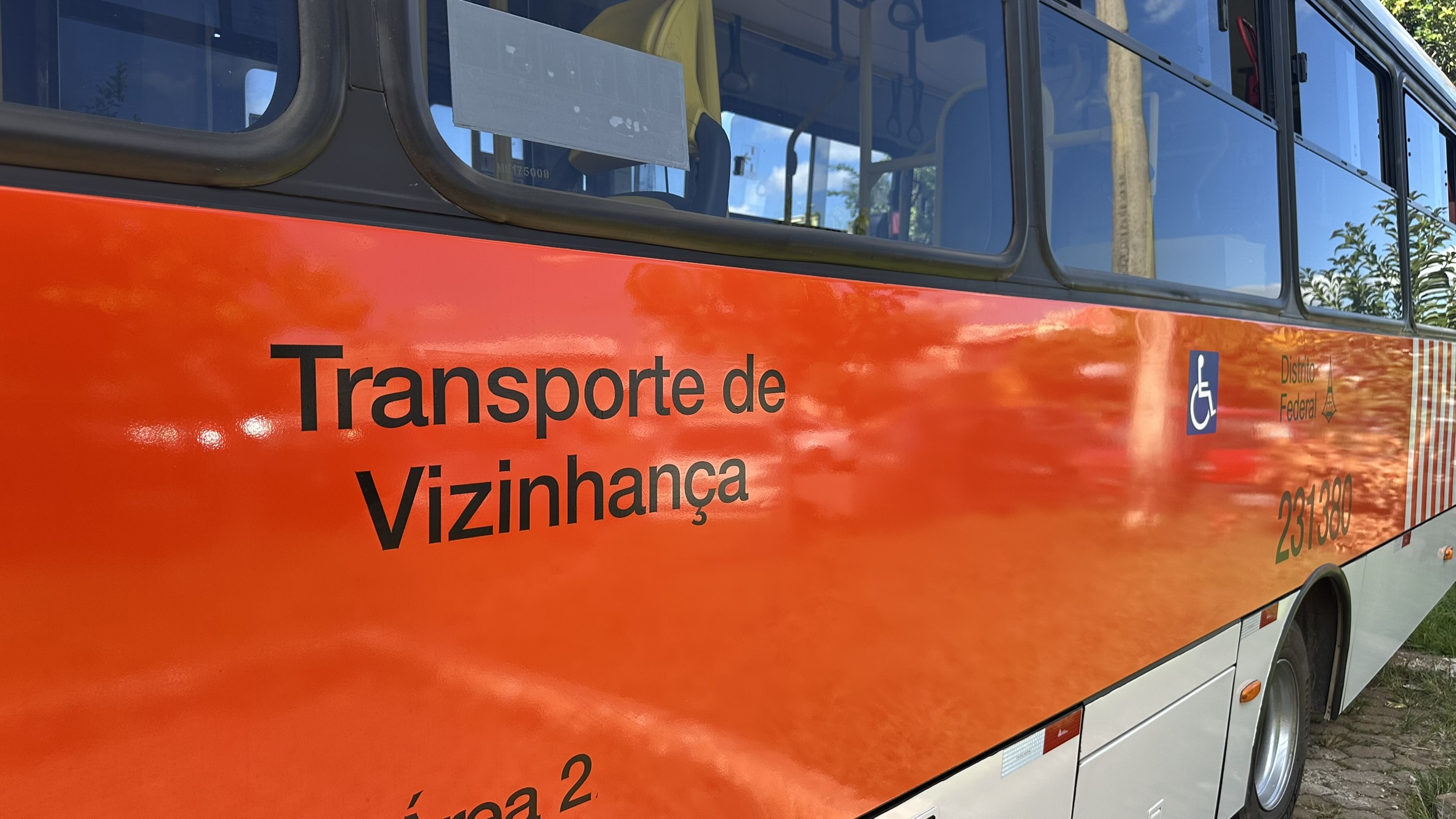 Lateral de um ônibus laranja do serviço Transporte de Vizinhança do Distrito Federal