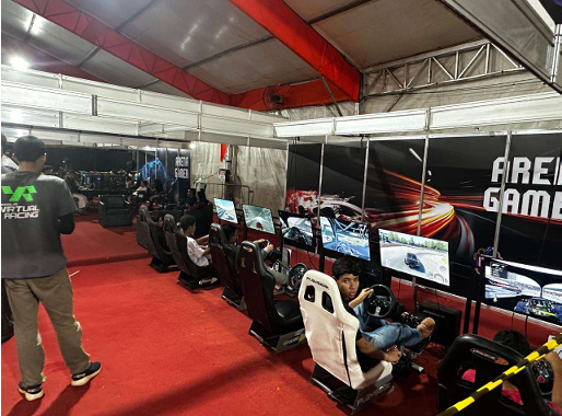 Visitantes usam simuladores de corrida com telas e cadeiras em uma arena de jogos eletrônicos
