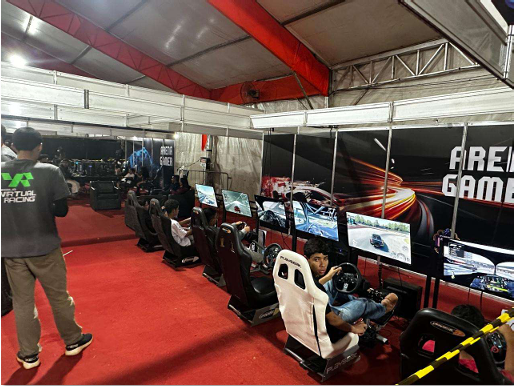 Visitantes usam simuladores de corrida com telas e cadeiras em uma arena de jogos eletrônicos