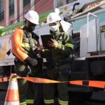 Profissionais com equipamentos de segurança trabalham ao lado de veículo de manutenção elétrica