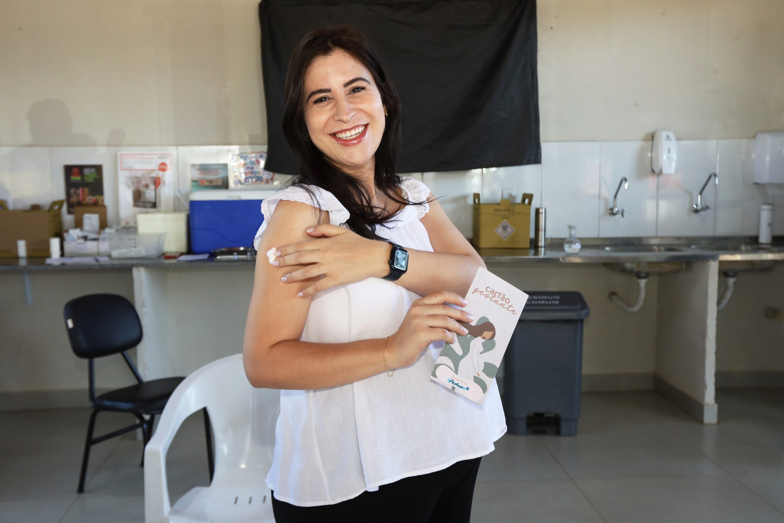 Gestante segura caderneta após receber vacina em unidade de saúde do DF