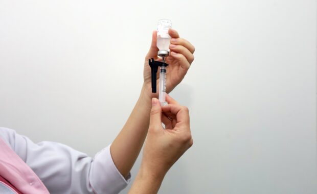Profissional de saúde prepara uma dose de vacina em seringa