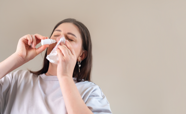 Mulher utiliza solução nasal enquanto segura um lenço próximo ao rosto