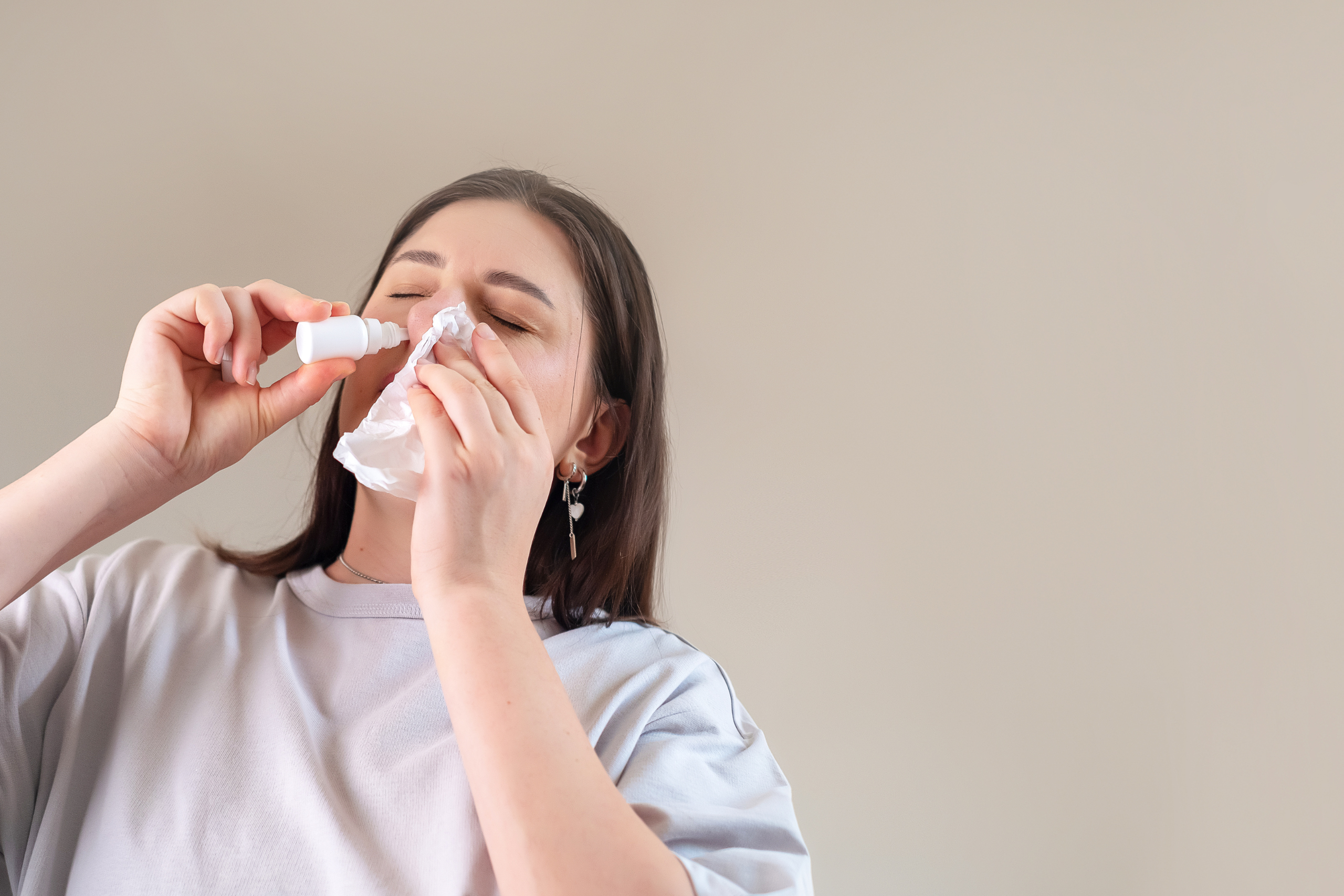 Mulher utiliza solução nasal enquanto segura um lenço próximo ao rosto