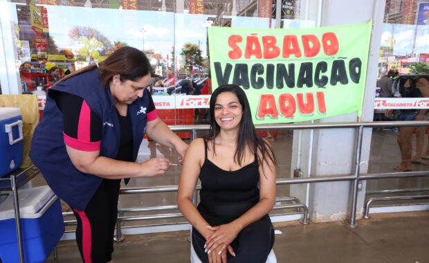 Profissional de saúde aplica uma vacina no braço de uma mulher