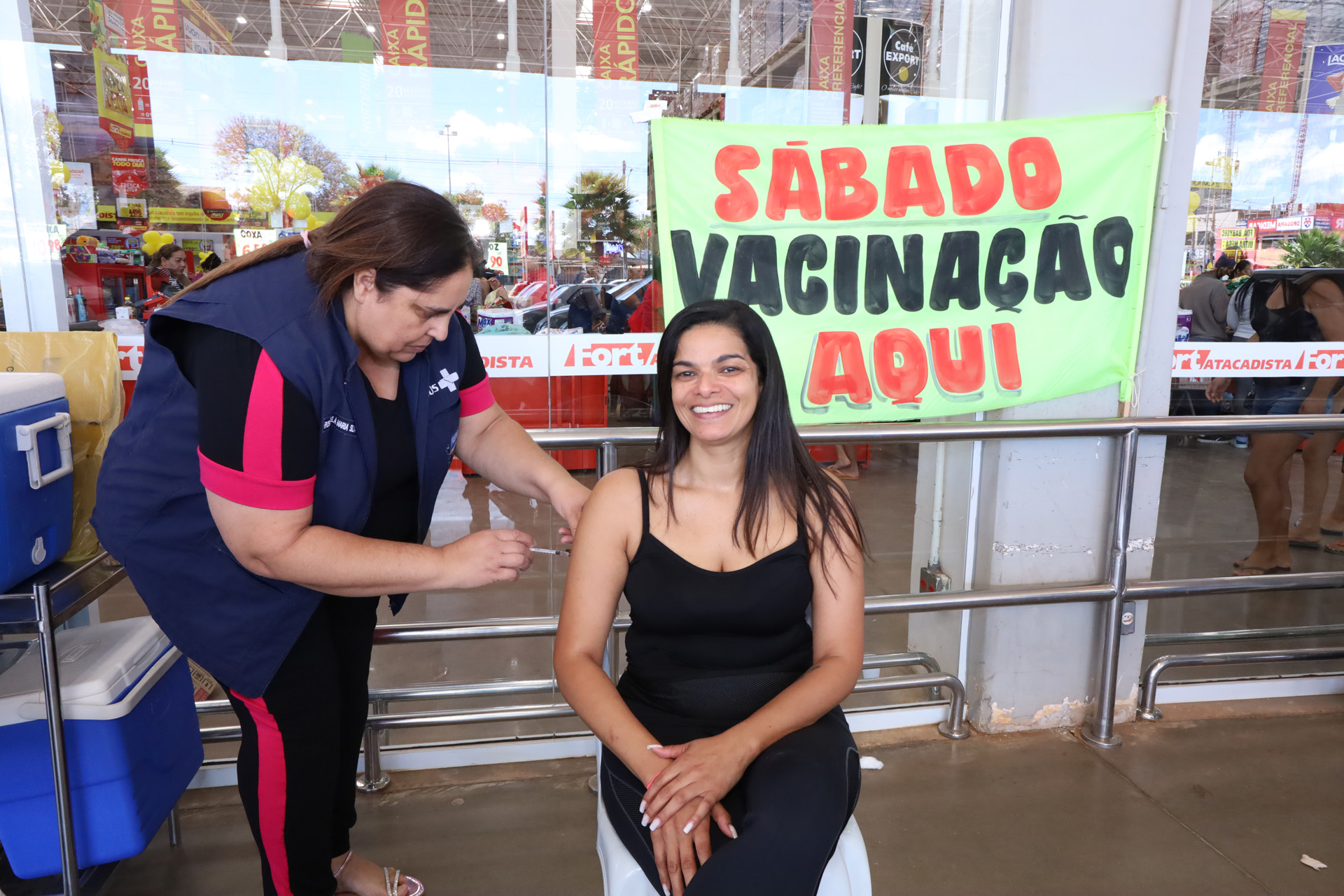 Profissional de saúde aplica uma vacina no braço de uma mulher