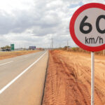 Marginal da BR-040 sinalizada ao lado de placa de velocidade máxima de 60 quilômetros por hora