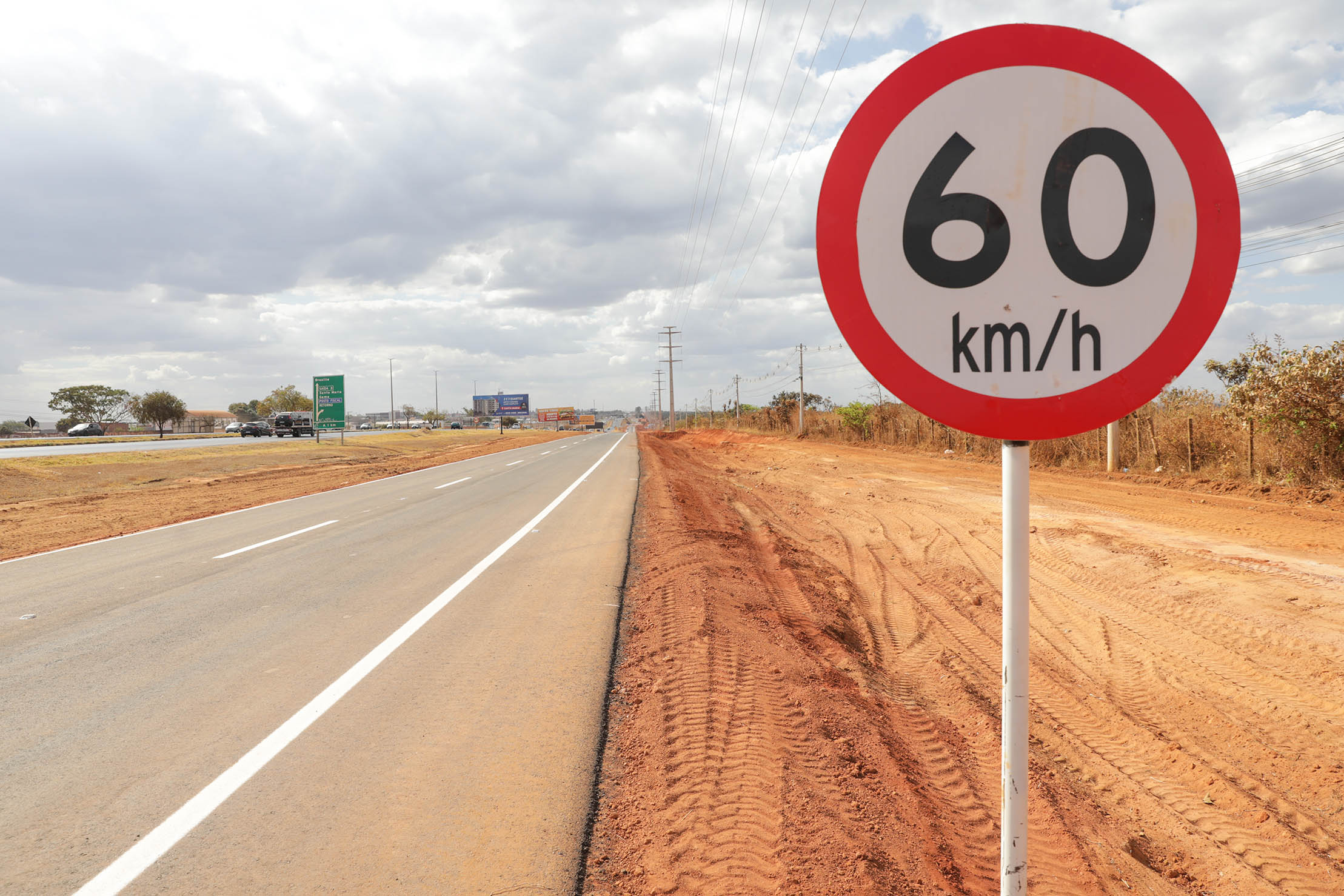 Marginal da BR-040 sinalizada ao lado de placa de velocidade máxima de 60 quilômetros por hora