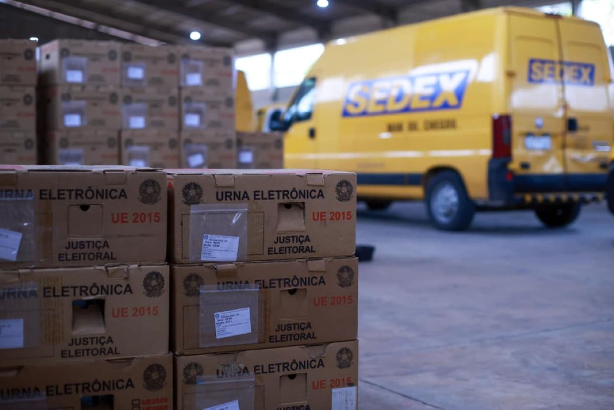 Caixas com urnas eletrônicas ao lado de veículos usados no transporte