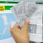 Consumidor segura notas fiscais diante da página do programa Nota Legal